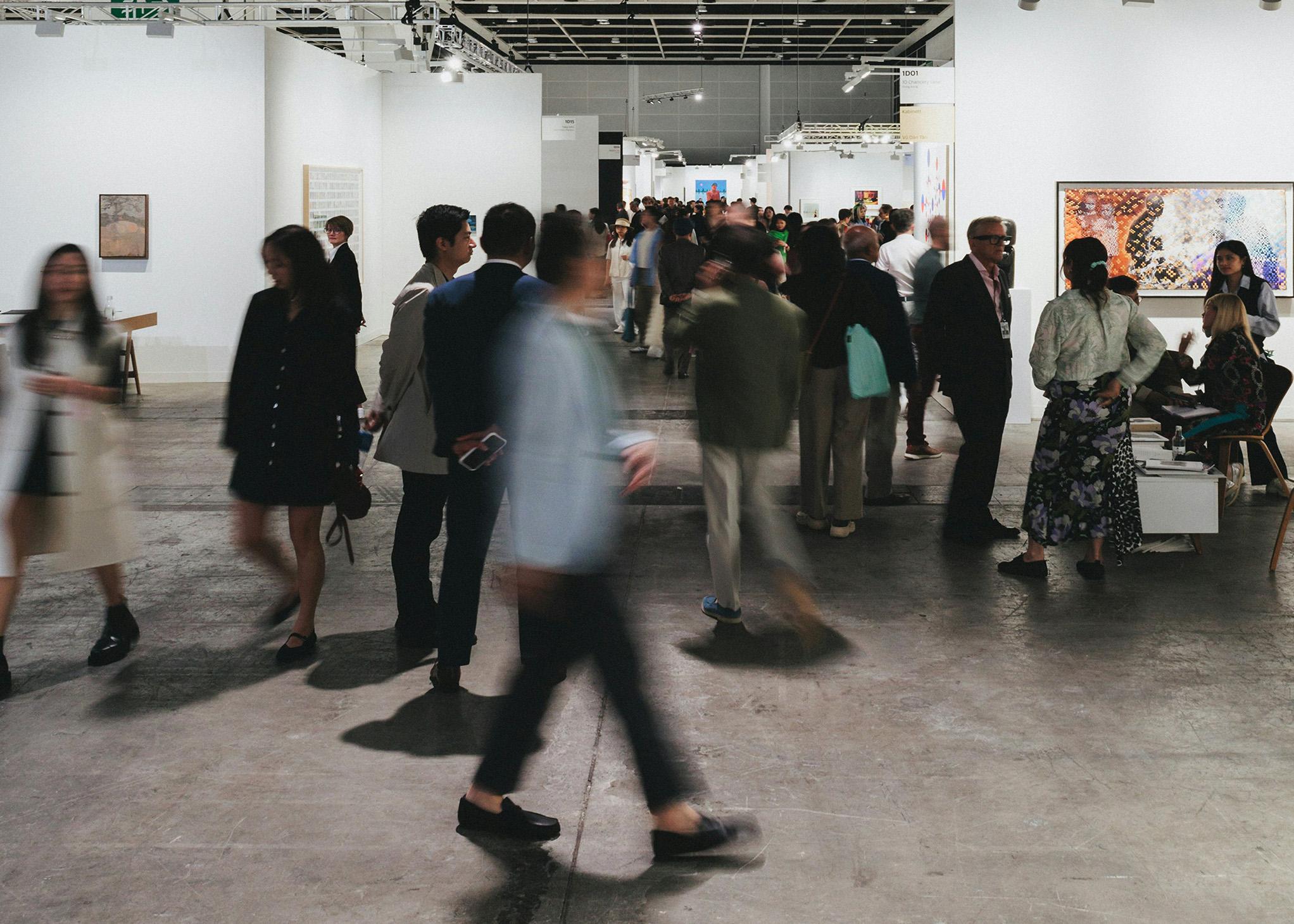 Visitors moving through a busy art fair hall