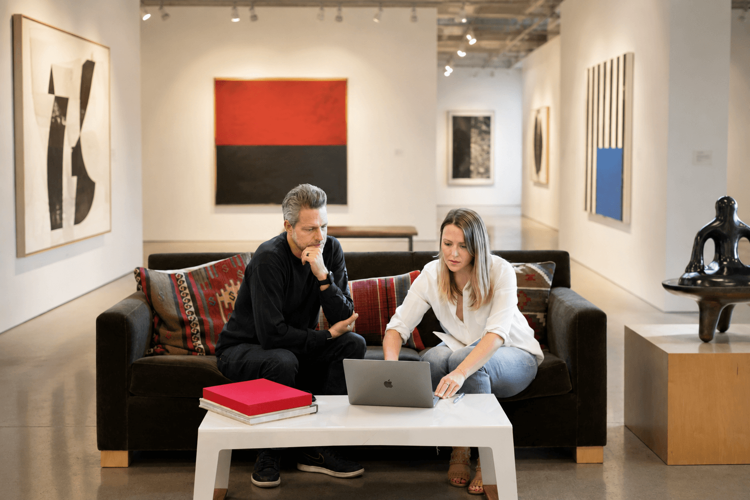 Advisor and collector reviewing works together on a laptop in a gallery.