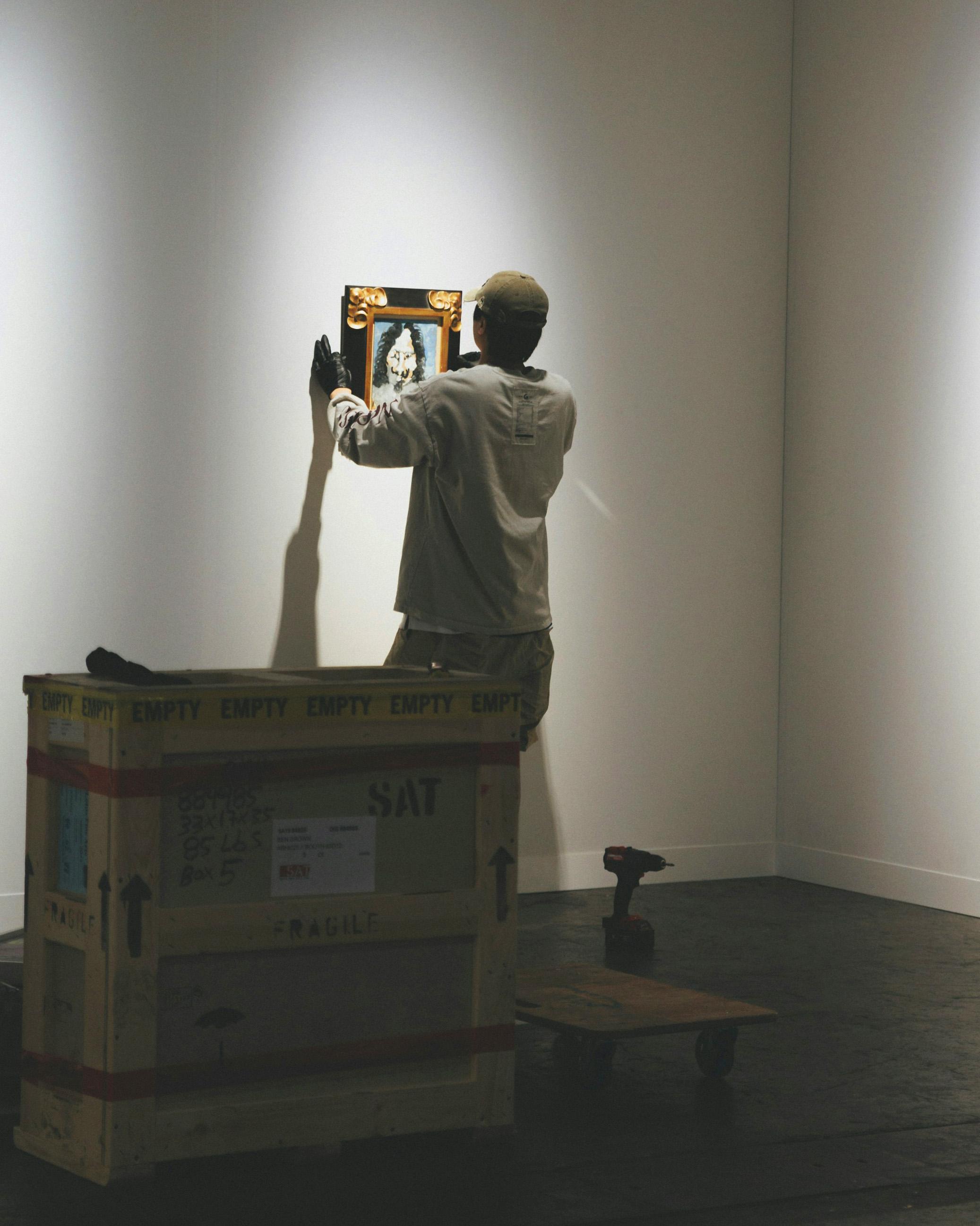 Technician hanging a framed artwork on a gallery wall