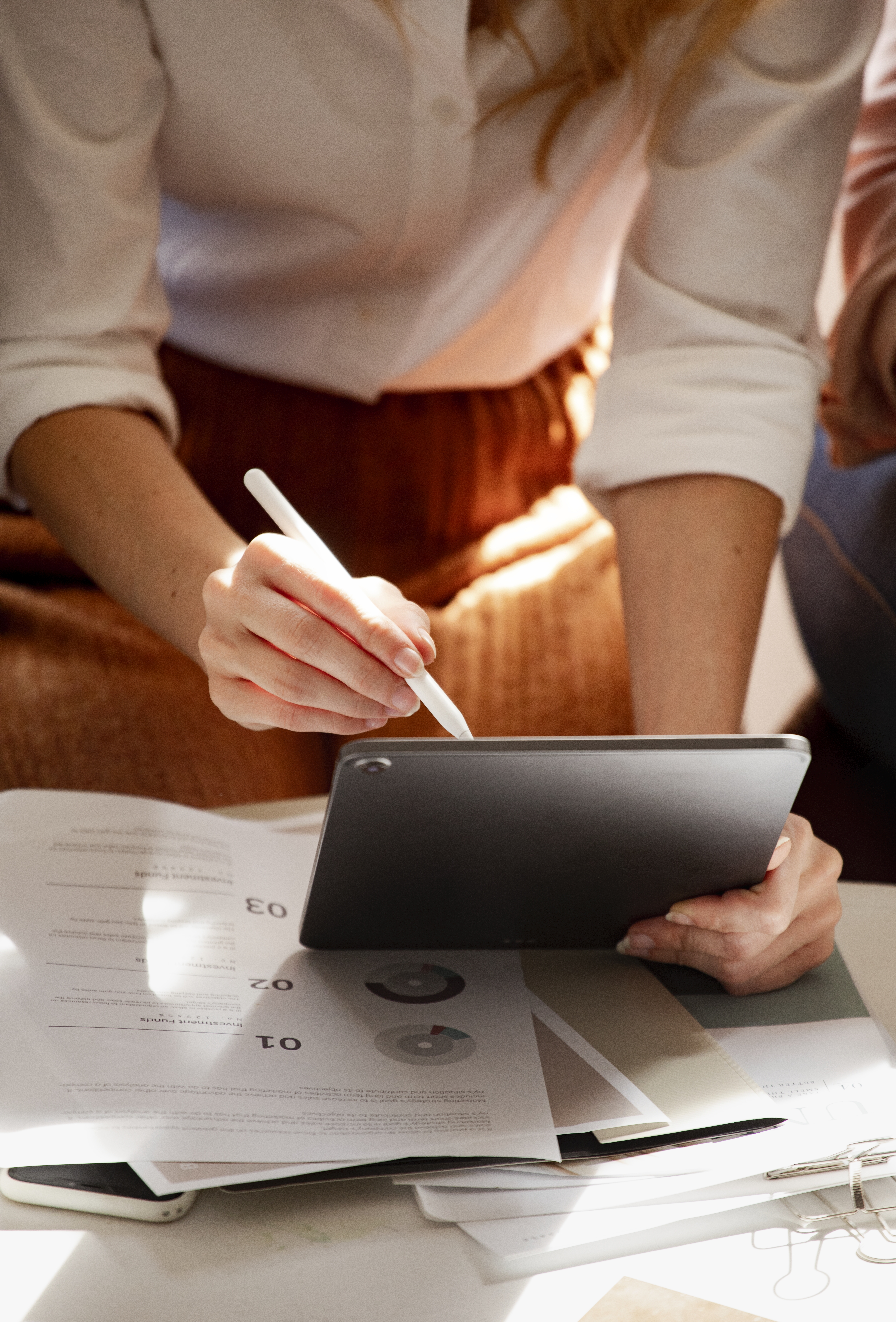 Artist working on a tablet with a stylus alongside paperwork